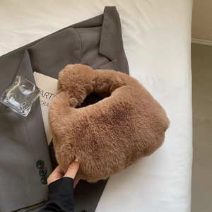 Gros plan d'un sac à main en peluche marron avec anse torsadée sur blazer gris