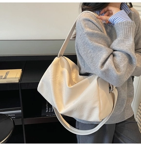 Détail d'un sac à bandoulière en cuir texturé blanc crème avec large sangle sur modèle