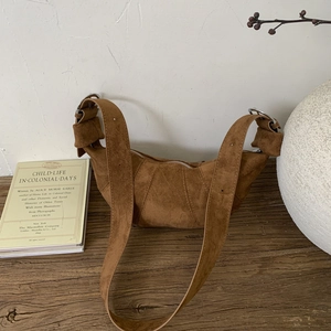 Detailed view of the brown suede crescent bag with a matte finish and silver hardware buckle
