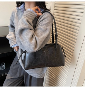 Detail of black vintage tote bag featuring silver buckle strap and side drawstring knot