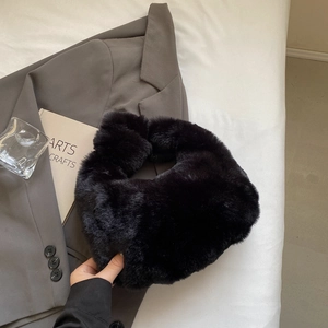 Détail d'un sac à main noir en fausse fourrure avec une texture douce et un design épuré