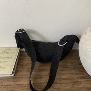 Detail of black matte leather crescent bag with adjustable wide strap and silver metal buckle