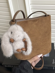 Chic brown suede bucket bag with leather handles and cute rabbit charm on side