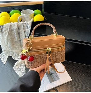 Detailed close-up of a woven box bag with leather trim and red cherry charm