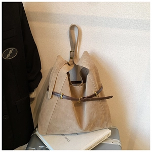 Detail of beige suede tote bag with brown strap decoration and golden metal buckle