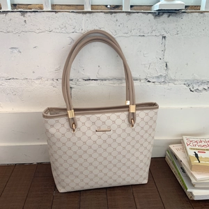 Detail of minimalist cream tote bag with geometric print and gold metal hardware accents