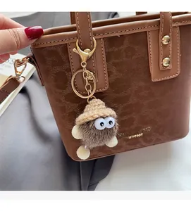 Détail d'un sac cabas marron texturé avec garniture dorée et breloque en peluche