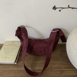 Detailed close-up of burgundy frosted suede dumpling bag with pleated crescent design