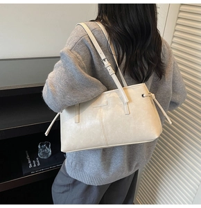 Close-up of cream leather shoulder bag featuring adjustable strap and minimalist side drawstring
