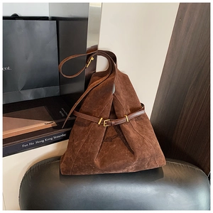 Detailed close-up of dark brown suede tote bag with elegant gold metal buckle and strap