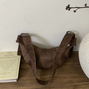 Detail of retro dark brown suede croissant bag with silver buckle on a wooden table
