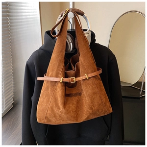 Close-up of brown suede tote bag with golden metal buckle and leather belt detail