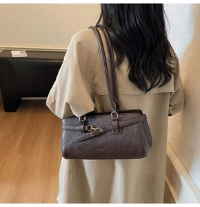 Detail showing the dark brown retro shoulder bag with buckle design on a model