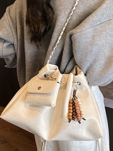 Chic cream white drawstring bucket bag with beaded charm and braided chain strap
