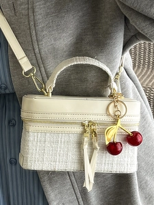 Mini cream tweed box crossbody bag with cherry charm shown on a casual blazer outfit