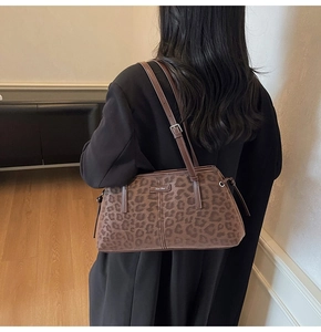 Chic leopard print shoulder bag worn by model, featuring slim straps and a metal logo tag