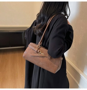 Detail view of the brown leather shoulder bag with side buckle and vintage metal hook design