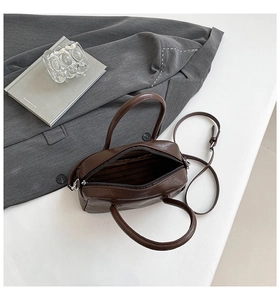 Detail view of dark brown Boston bag with soft leather texture and striped lining interior