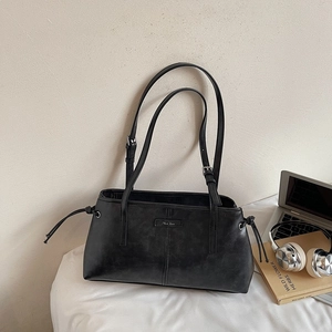Detail of black faux leather shoulder bag with dual straps and side drawstring accents
