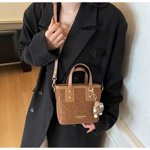 Détail du mini sac cabas marron à motif léopard avec breloque et logo doré élégant