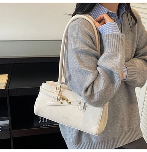 Detail showing creamy beige textured leather shoulder bag with gold metal buckle