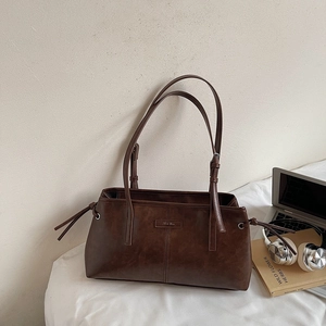 Detailed view of dark brown tote bag with Mom Ricu label and side tassel drawstrings