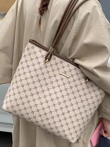 Minimalist beige tote bag with geometric print and brown straps worn by a model in a trench coat