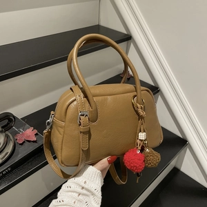 Detail of camel brown Boston bag featuring pleated texture and decorative plush charms
