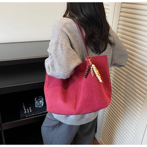 Detail view of large burgundy suede tote bag with decorative colorful beaded tassels