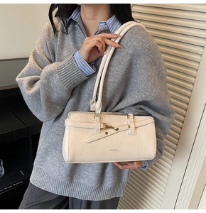 Detail of the cream-white faux leather handbag with golden metal buckles and texture