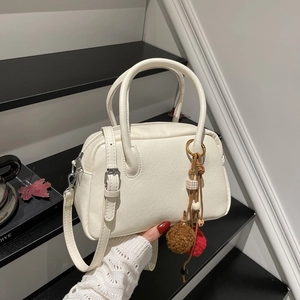Macro shot of creamy Boston bag with lychee texture leather and decorative pendant