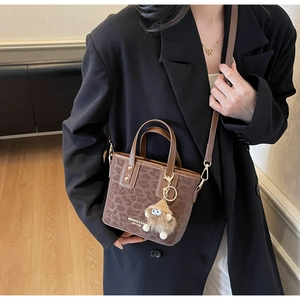 Détail du sac bandoulière léopard vintage avec breloque en peluche et logo de marque