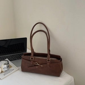 Brown vintage leather shoulder bag detail with laptop and silver headphones on desk