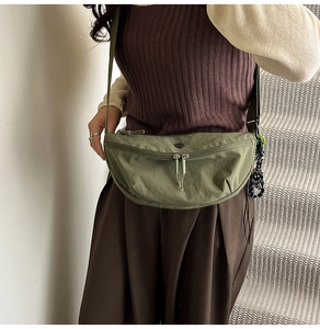 Detailopname van de legergroene nylon halve maan tas met dubbele rits en smiley hanger