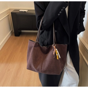 Detail of dark brown suede tote bag with colorful beaded charm and slim shoulder straps