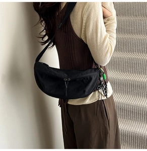 Detail van zwarte nylon halvemaantas met verstelbare brede riem en sierketting