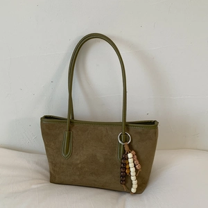 Detail of olive green suede tote bag with contrast stitching and beaded charm accessory