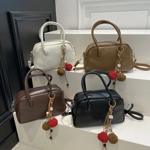 Detail showing four colors of Korean Boston bags with stylish plush charms on white steps