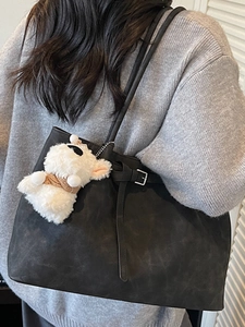Minimalist black matte tote bag with sheep plush charm shown on person's shoulder