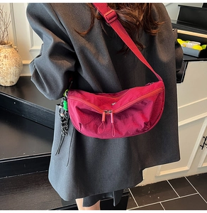 Donkerroze nylon halve maan crossbodytas op model met groen koorddetail en ritsen