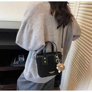 Détail du sac bandoulière noir à motif léopard avec pendentif en peluche et boucles dorées