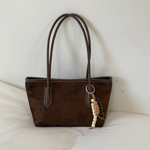 Close-up of deep coffee suede tote bag with stylish ethnic beaded charms and leather trim