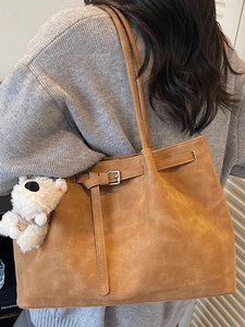 Minimalist dark brown oversized tote bag with decorative buckle and white bear charm