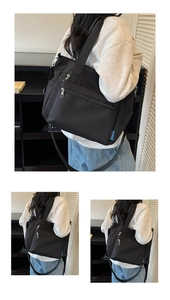Close-up of black nylon tote bag featuring multiple front zippers and side pocket detail