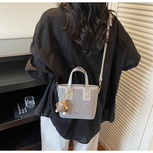 Vue détaillée d'un petit sac seau bleu-gris avec un gri-gri et l'emblème de la marque