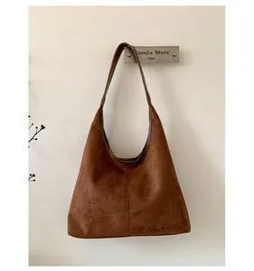 Detail view of a vintage brown suede hobo bag hanging on a minimalist wall hook