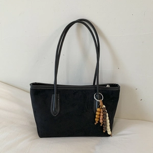 Detail of black suede tote bag with ethnic wooden bead charm and long double handles