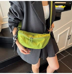 Detail van een grasgroene nylon halve maantas gedragen over een donkergrijs jasje