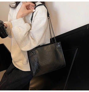 Vista dettagliata della borsa tote trapuntata nera con tracolla a catena indossata a spalla