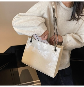 Dettaglio della borsa tote crema trapuntata a V con tracolla a catena in metallo nero